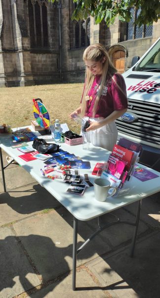 Photo of Likewise staff member standing outside the cathedral with a stall, filled with leaflets
